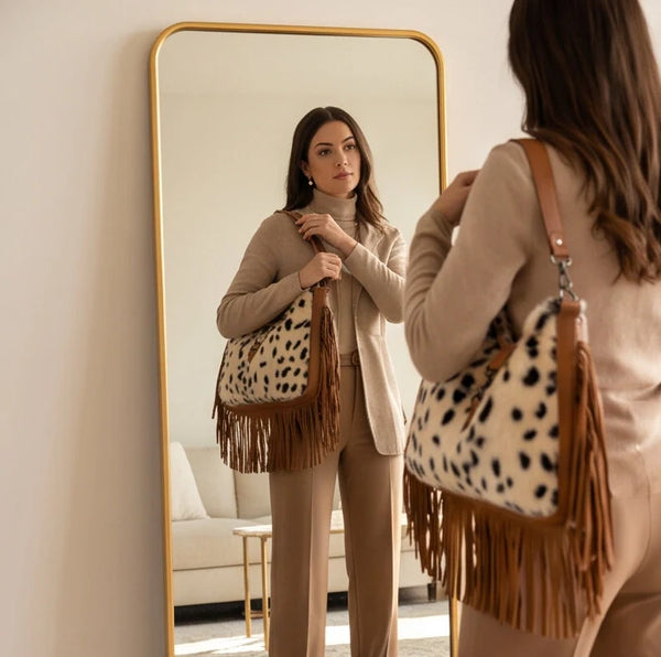 Borsa hobo animalier con frange indossata a spalla davanti a uno specchio