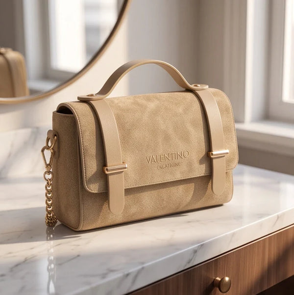 Borsa Valentino Creations tortora con manico e catena appoggiata in un ambiente luminoso