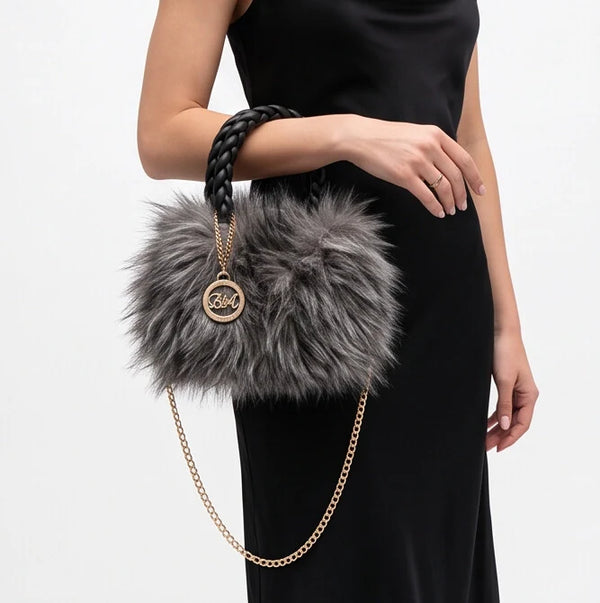 Mini borsa antracite con manici intrecciati portata al polso con un abito nero